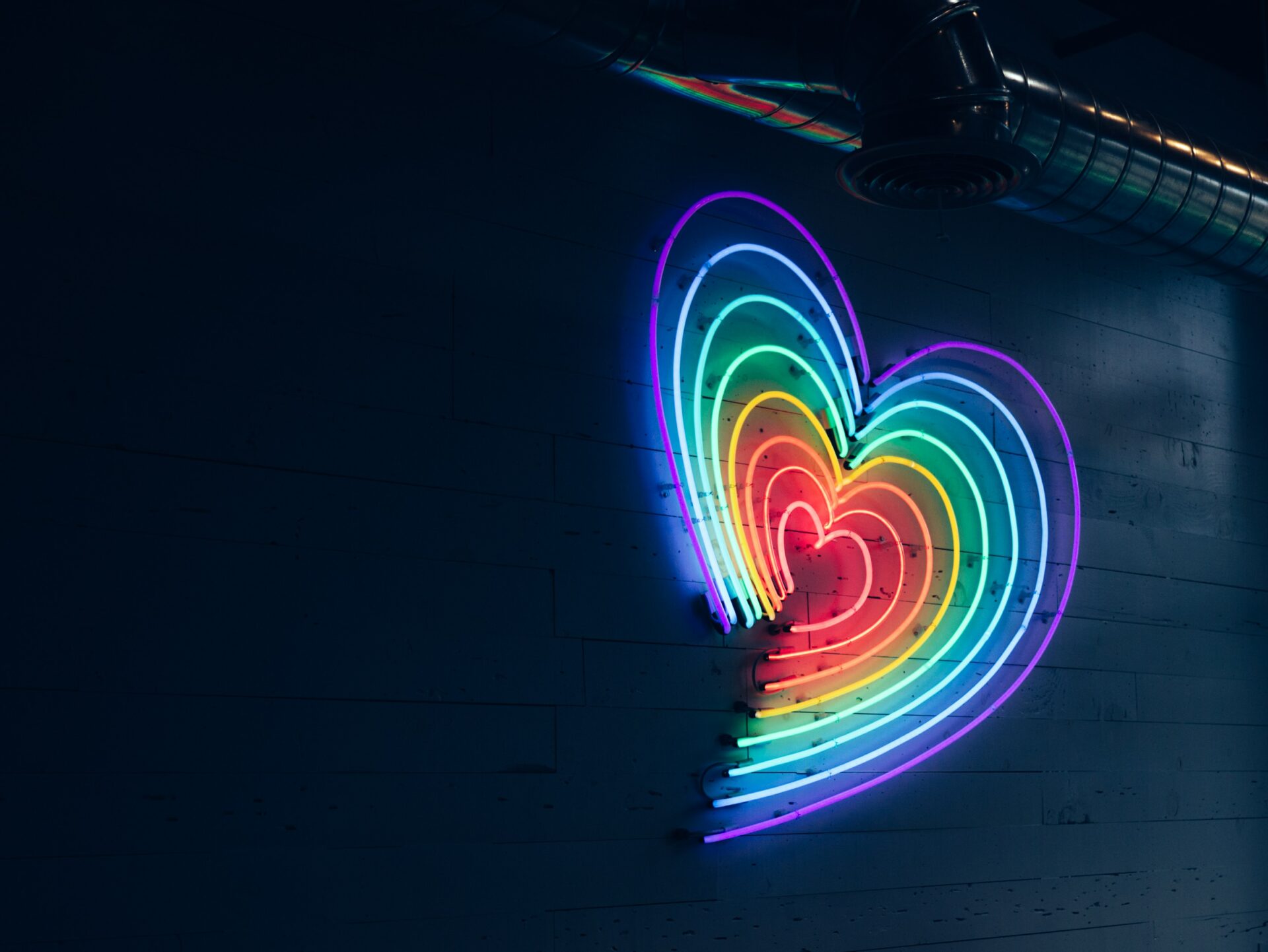a glowing neon sign in the shape of a rainbow heart
